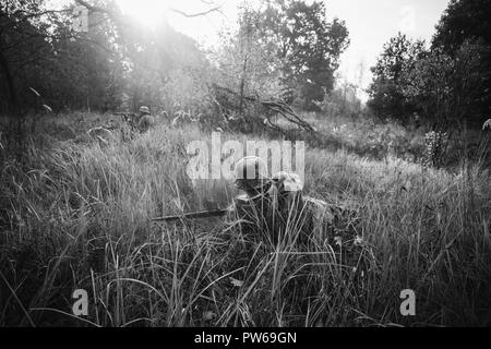 Nicht identifizierte Re-Enactor verkleidet als Soldat der deutschen Wehrmacht Infanterie im zweiten Weltkrieg versteckt sitzen mit Gewehr Waffe In einem Hinterhalt In Graben im Herbst Stockfoto