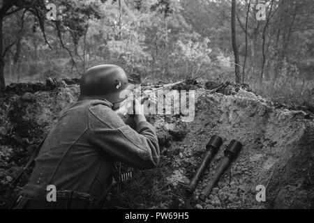 Nicht identifizierte Re-Enactor verkleidet als Soldat der deutschen Wehrmacht Infanterie im zweiten Weltkrieg versteckt sitzen mit Gewehr Waffe In einem Hinterhalt In Graben im Herbst Stockfoto