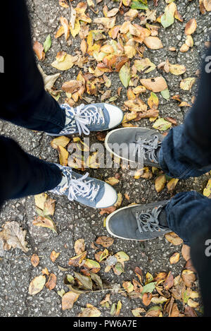 Obere Blick auf die Füße von Mann und Frau, die im Herbst unter getrocknet oder fallen lässt. Stockfoto