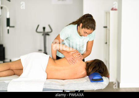 Professionelle female Physiotherapeut die Schulter Massage Frau im Krankenhaus zu brunette. Medizinische Check an der Schulter in der Physiotherapie. Stockfoto