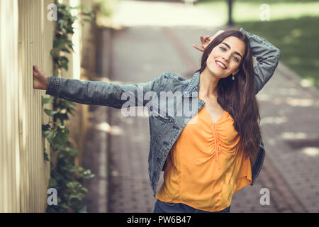 Junge Frau mit schönem Haar legere Kleidung im städtischen Hintergrund. Happy girl mit gewellten Frisur. Stockfoto