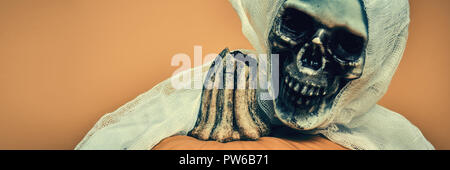 Spooky Halloween Konzept. Scary skeleton umarmt jack o lantern Kürbis. Halloween Banner. Stockfoto
