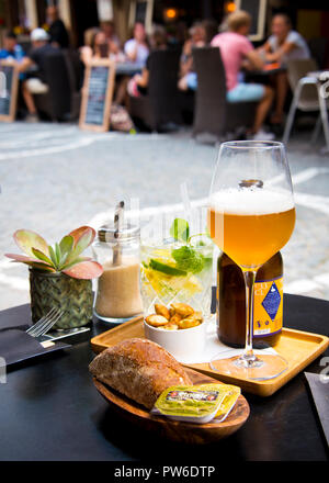 Vorspeisen, alkoholische Getränke, Bier in Gläsern auf runden kleinen Tisch im Freien, Gruppen von Menschen im Hintergrund sitzen im Café gegenüber, Stockfoto