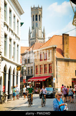 Kleine Straße hinter der Straße, in der Altstadt von brügge, Leute laufen, junges Paar auf Fahrrädern genießen eine langsame Fahrt durch Kopfsteinpflaster Straßen, Belgien, Stockfoto