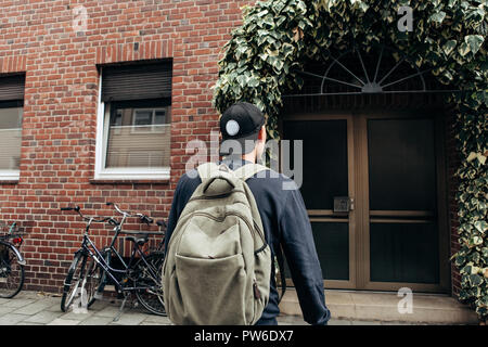 Ein Tourist geht in die Pension oder Herberge, um in ein Zimmer, dass er gebucht oder ein Student mit einem Rucksack kehrt nach seinem Studium am Institut oder auf Urlaub. Stockfoto