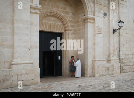 Ein katholischer Priester im Gespräch mit einem Mitglied der Versammlung nach der Sonntagsmesse in der Parroquia de Nuestra Señora Del Rosario, Es Castell, Menorca, Spanien Stockfoto