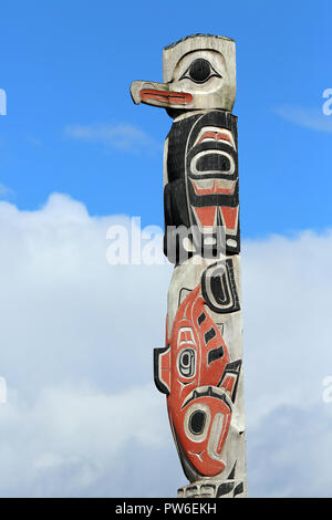 Native American Bird und Lachs Motiv Totempfahl mit rotem Hintergrund, Stockfoto