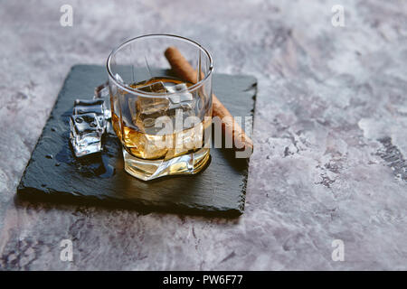 Glas Whisky mit Eiswürfel und Zigarre Stockfoto