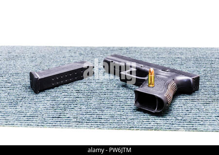 Auf diesem Bild sehen Sie die Pistole Pistole, leeres Magazin, eine Kugel 9 mm Verlegung auf dem grau blau Teppich. Stockfoto