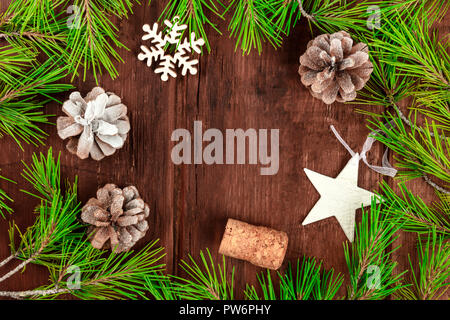 Weihnachten Hintergrund mit Fir Tree Branches, Kegel, Schnee, Weihnachten Dekorationen und ein Korken, auf einem dunklen rustikalen Textur mit Kopie Raum Stockfoto