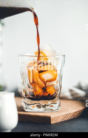 Gießen kalten Espresso in ein Glas mit Eiswürfeln in eine moderne Küche in den Morgen. Stockfoto