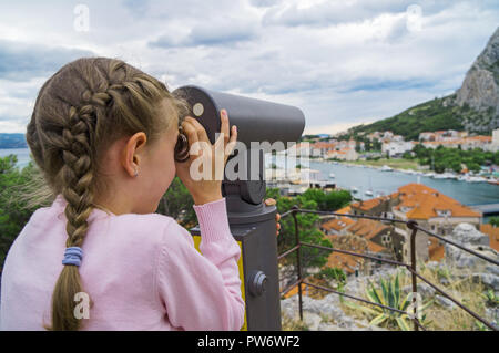 Kleines Mädchen mit Münze betrieben Panorama Teleskop. Stockfoto