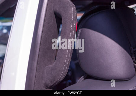 Eine Nahaufnahme von einem schwarzen Griff aus Kunststoff an der Decke in einem Auto in einem Beifahrersitz mit einem schwarzen Tuch aus weichem Leder in der Werkstatt von einem Tuning gezogen Stockfoto