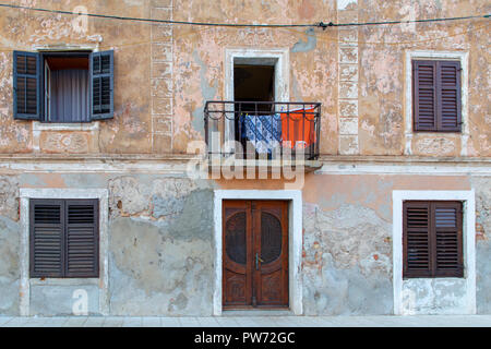 Ein traditionelles Haus in Kroatien mit hölzernen Türen, Fensterläden aus Holz und einem kleinen Balkon mit Hemden auf dem Trockenen sitzen Stockfoto