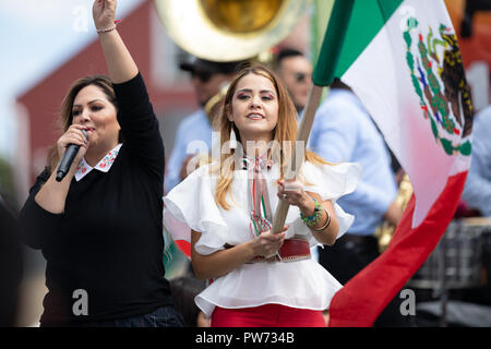 Chicago, Illinois, USA - 9. September 2018 der 26. Straße mexikanische Unabhängigkeit Parade, junge Frau winkte einen großen mexikanischen Flagge auf einem Schwimmer Stockfoto