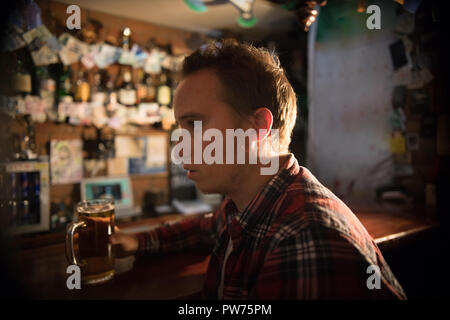 Nachdenklicher junger Mann an der Bar mit einem Pint Bier Stockfoto