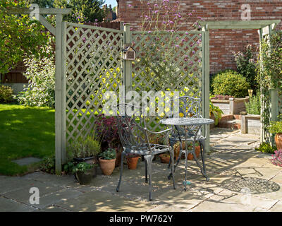 Kleine inländische Garten Terrasse mit Tisch und Stühlen, Natursteinplatten und lackierte Gitter Stockfoto