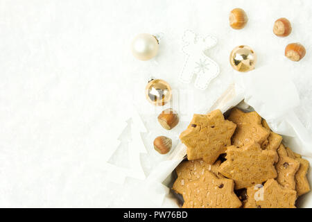 Weihnachten Shortbread Cookies mit Haselnüssen in Sternform in Holzkiste. Weiß Ornamente Tanne Hirsch goldenen Kugeln auf verschneiten Hintergrund. Holiday bakin Stockfoto