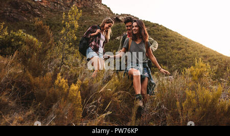 Eine Gruppe von Freunden zu Fuß durch unwegsames Gelände. Zwei Frauen und ein Mann Wandern auf einem Rocky Mountain Trail. Stockfoto