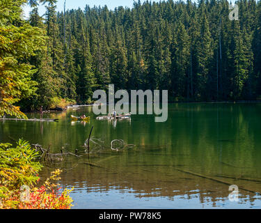 Drei nicht identifizierte junge Männer und ein Hund genießen Sie die Gewässer des Oregon Hideaway Lake im frühen Herbst. Stockfoto