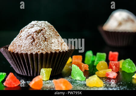 Frisch gebackene Muffins mit kandierten Früchten auf einem Schwarzen Tisch Stockfoto