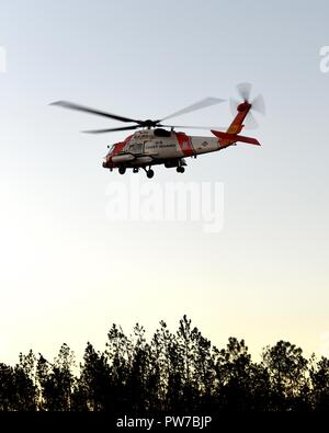Der Küstenwache MH-60 Jayhawk Helikopter Crew bietet Mission - wesentliche Lieferungen zu Küstenwache personal Okt.12, 2018, in Panama City, Florida. Coast Guard Besatzungen aus in den USA sind strategisch Verlagerung von Personal und Assets für Hurrikan Michael post-Sturm Antwort. (U.S. Coast Guard Foto von Petty Officer 3. Klasse Jäger Medley) Stockfoto