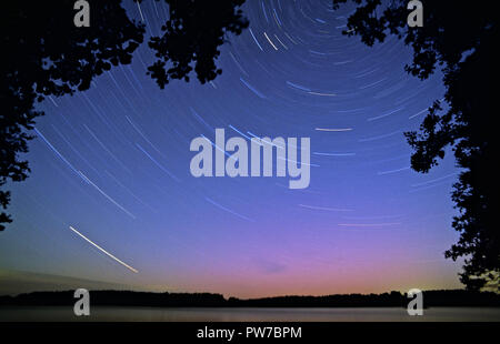 Lange Belichtung star Trails, Drehung um die North Star. Aurora Borealis leuchtenden grünen und roten über dem Horizont. Stockfoto