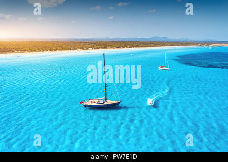 Yachtcharter an der azurblauen Küste in Balearen. Luftaufnahme von schwimmenden Segelboot und Motorboot in transparenten Meer bei Sonnenuntergang im Sommer. Blick von oben Stockfoto