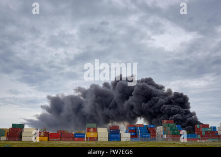 Eine Feder der giftige Rauch bei einem West Footscray Fabrik Feuer von hinter dem Container gesehen. Melbourne, Victoria, Australien, 30. August 2018. Stockfoto