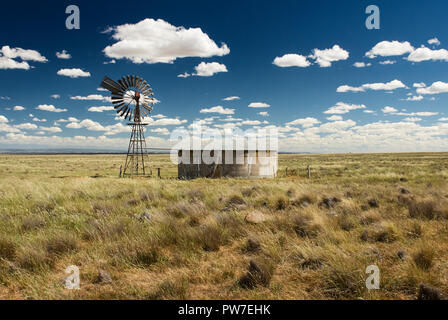 Alten retro Mühle Wasserpumpe und Stahlbeton im australischen Outback auf einen schönen Sommer sonnigen Tag mit weißen puffy Clouds. Stockfoto