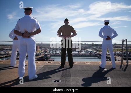 NORFOLK, Virginia (Sept. 23, 2017) Matrosen und Marines zu den amphibischen Angriff Schiff USS Bataan (LL 5) man die Schienen, wie das Schiff wieder in den Heimathafen. Er Schiffes aus dem geplanten Einsatz zur Unterstützung der Maritime Security Operations und Theater Sicherheit Zusammenarbeit in Europa und im Nahen Osten wieder zugewiesen. Stockfoto