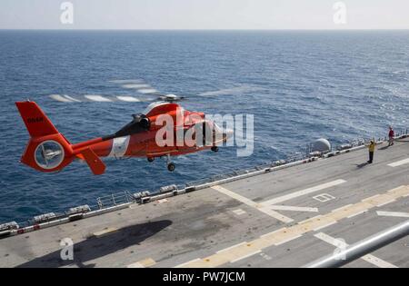 Karibik (Sept. 24, 2017) eine US Coast Guard MH-60 Dolphin Hubschrauber hebt ab nach dem Tanken auf dem Flugdeck an Bord der Amphibisches Schiff USS Kearsarge (LHD3). Kearsarge unterstützt mit Hilfsmaßnahmen in den Wirbelsturm Maria. Das Verteidigungsministerium ist die Unterstützung der Federal Emergency Management Agency, die Leitung der Föderalen Agentur bei der Unterstützung der Betroffenen durch den Hurrikan Maria Leiden zu minimieren und ist ein Bestandteil der gesamten-von-Reaktion seitens der Regierung. Stockfoto