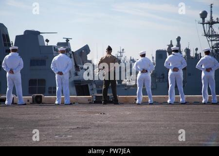 NORFOLK, Virginia (Sept. 23, 2017) Matrosen und Marines zu den amphibischen Angriff Schiff USS Bataan (LL 5) man die Schienen, wie das Schiff wieder in den Heimathafen. Er Schiffes aus dem geplanten Einsatz zur Unterstützung der Maritime Security Operations und Theater Sicherheit Zusammenarbeit in Europa und im Nahen Osten wieder zugewiesen. Stockfoto