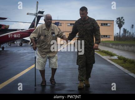 Us Marine Gunnery Sgt. Philip C. Sackett, mit Joint Task Force - Leeward Inseln, Escorts US-Bürger zur Evakuierung Control Center an Douglas-Charles Flughafen in Dominica, Sept. 24, 2017. Das Control Center wurde eingerichtet, die in den freiwilligen Evakuierung von US-Bürgern auf Dominica gestrandet nach Hurrikan Maria zu unterstützen. Auf Anfrage der Partnerländer und sowohl das State Department und der US-Agentur für Internationale Entwicklung, JTF-LI hat Flugzeuge und Service Mitglieder zu den Bereichen in der östlichen Karibik bereitgestellt, die von den Hurrikanen Irma und Maria. Die Task Force ist eine US-amerikanische Mili Stockfoto