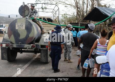 Us-Soldaten in die Puerto Rico Nationalgarde zugewiesen, zusammen mit Mitarbeitern aus den Wasserleitungen und Kanalisation Behörde von Puerto Rico, Wasser für die Gemeinden Utuado, Puerto Rico, Sept. 26, 2017 verteilen. Nach dem Aufprall des Hurrikans Maria, 2.175 Service Mitglieder, einschließlich der Puerto Rico National Guard, hatte im Gebiet bereitgestellt, um die Anstrengungen der Regierung für den Wiederaufbau der Insel zu unterstützen. Stockfoto