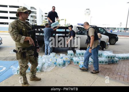 Eine taktische Strafverfolgungsbehörden Team Süd, Miami, crewmember, Coast Guard Investigative Service Agenten und Federal Air Marshal Service Agenten Wasser für die Menschen an Bord Flüge San Juan (Puerto Rico) International Airport, Sept. 26, 2017 warten. Als Teil der Abteilung für Homeland Security Team, die Küstenwache ist direkt an das FEMA und die gesamte Bundesregierung Hurrikan recovery Phase des Hurrikan Maria Reaktion verknüpft. Stockfoto