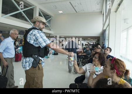 Ein Coast Guard Investigative Service Agent liefert Wasser für die Bewohner von San Juan, Puerto Rico, Sept. 26, 2017. Als Teil der Abteilung für Homeland Security Team, die Küstenwache ist direkt an das FEMA und die gesamte Bundesregierung Hurrikan recovery Phase des Hurrikan Mariaresponse verbunden. Stockfoto