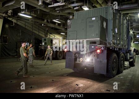 Karibik (Sept. 26, 2017) Marines bis 26 Marine Expeditionary Unit Load Fahrzeuge, die Generatoren und andere Geräte auf eine Landing Craft Utility innerhalb des Amphibisches Schiff USS Kearsarge (LHD 3) Gut deck zugewiesen, für den Transport in Puerto Rico. Kearsarge und der 26 MEU unterstützen mit Hilfsmaßnahmen in den Wirbelsturm Maria. Das Verteidigungsministerium ist die Unterstützung von FEMA, die Leitung der Föderalen Agentur, dabei helfen, die Betroffenen durch den Hurrikan Maria Leiden zu minimieren und ist ein Bestandteil der gesamten-von-Reaktion seitens der Regierung. Stockfoto