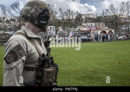 Eine Luft- und Marine Operations Agent schaut auf eine Masse, die mit einem Jungen fliegen die Puerto Rican Flag nach der Landung in Aibonito am Sonntag, den 24. September. Us-amerikanischen Zoll- und Grenzschutz Stockfoto