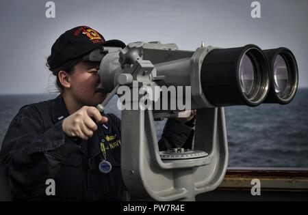 Ostsee (Sept. 26, 2017) Lt. j.g. Jeanette Moutray scannt den Horizont mit dem Fernglas an Bord der Arleigh-Burke-Klasse geführte Anti-raketen-Zerstörer USS Oscar Austin (DDG79) Sept. 26, 2017. Oscar Austin auf einer routinemäßigen Bereitstellung unterstützen die nationale Sicherheit der USA Interessen in Europa und der zunehmenden Theater Sicherheit gute Zusammenarbeit und freuen uns naval Präsenz in den USA 6 Flotte Bereich der Operationen. Stockfoto