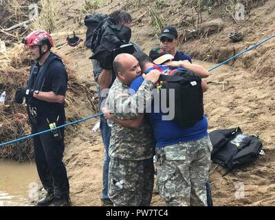 UTUADO, Puerto Rico, Sept. 26, 2017 - Mitglieder des New York Task Force 1 und der Puerto Rico nationale eine Familie von fünf in der Nähe von Utuado, Puerto Rico, Sept. 26 evakuiert. New York Task Force 1 ist Teil des Nationalen Städtischen Suche und Rettung Response System unter der Aufsicht der Federal Emergency Management Agency. Stockfoto