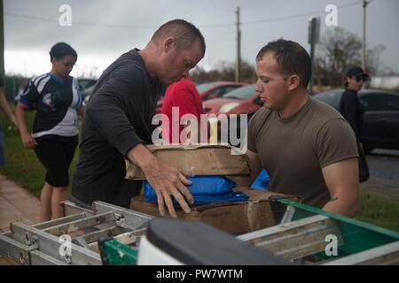 U.S. Army Staff Sgt. Ryan Hinojosa, zugeordnet zu den 101 Combat Aviation Brigade (CAB), Luftlandedivision (Air Assault), hilft tarps in die Gemeinschaft Mehrzweckgebäude, Ceiba, Puerto Rico, Sept. 30, 2017. Die tarps werden verwendet, um die Dächer der Häuser, die vom Sturm betroffenen vorübergehend beheben. Die 101 CAB führt medizinische Evakuierung und Katastrophenhilfe FEMA im Wiederherstellungsprozess von Puerto Rico zu unterstützen nach der Verwüstung durch den Hurrikan Maria. Stockfoto