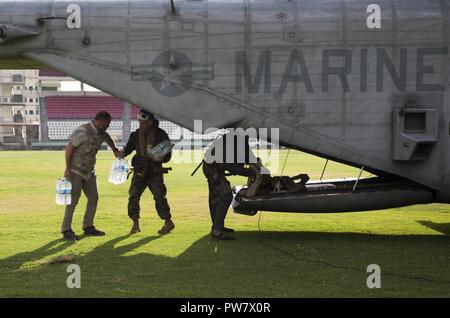 Us-Mitglieder mit Joint Task Force - Leeward Inseln Arbeit mit Mitgliedern der US-Agentur für Internationale Entwicklung Katastrophenhilfe Response Team Wasser aus der CH-53E Super Stallion Hubschrauber in Roseau, Dominica, Sept. 30, 2017 zu entladen. Auf Wunsch von USAID, JTF-LI hat eingesetzten Flugzeuge und Service Mitglieder in der Bereitstellung von Hilfsgütern zu Dominica in der Nachmahd des Hurrikans Maria zu unterstützen. Die Task Force ist in den USA eine militärische Einheit, die aus Marinen, Soldaten, Matrosen und Fliegern und stellt erste Reaktion US Southern Command zu den Hurrikanen, die beeinflussen Stockfoto