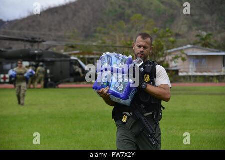 U.S. Coast Guard Investigative Service Agent, Ferdinand Acosta, trägt Wasser auf Bewohner in Utuado, Puerto Rico, Sept. 29, 2017. Als Teil der Abteilung für Homeland Security Team, die Küstenwache ist direkt an das FEMA und die gesamte Bundesregierung Hurrikan Recovery Phase der Reaktion auf den Hurrikan Maria verbunden. Stockfoto