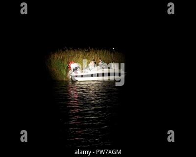 Ein Coast Guard 45-Fuß-Antwort Boat-Medium von Spotlight scheint auf drei Personen an Bord eines 19-Fuß-Boot in der Nähe von Nn, Nord-Carolina, Oktober 1, 2017. Die Frau von dem Mann an Bord der Yacht hatte den Mann und zwei Jungen fehlt wie pro Ihre float Plan berichtet. Crew von Station Hobucken entdeckte einen Flare von die drei Leute kurz nach dem Start nach ihnen zu suchen und entdeckte hatte das Schiff aus Gas laufen lassen. Station Hobucken crew abgeschleppt das Boot zurück nach einem lokalen privaten Dock, wo es günstig war und Familienangehörigen warteten auf die drei. Stockfoto