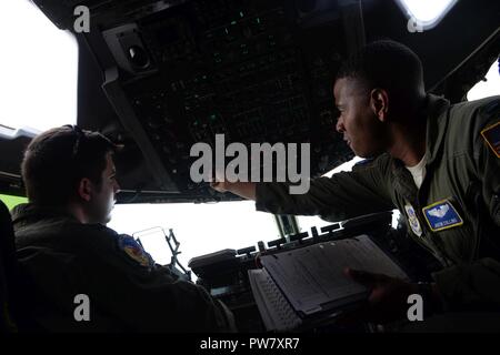 Kapitän Steve Quinn und 1 st. Lt. Justin Collins, 3d-Airlift Squadron erreichen 7170 Piloten, gehen durch Pre-flight Verfahren in einer C-17 Globemaster III vor dem Abheben in Fort Carson, Oberst Sept. 26, 2017. Reach 7170 ist Transport wesentliche Erholung Ausrüstung vom 68. Bekämpfung der Erhaltung Unterstützung Bataillon an die Überlebenden von Hurrikan Maria an Cyril E. Flughafen in St. Thomas, U.S. Virgin Islands. Stockfoto