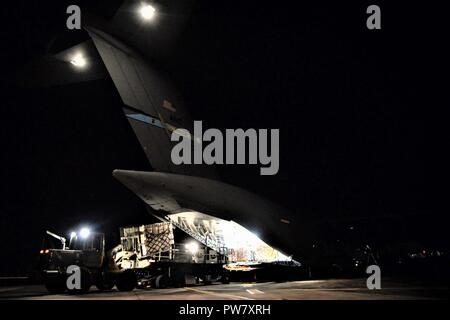 Die 3d-Luftbrücke der Squadron erreichen 7170 Crew und 123 Contingency Response Group Flieger entladen Essen und Wasser aus einem C-17 Globemaster III der Hurrikan Überlebenden von San Juan Luis Muñoz Marín Flughafen in San Juan, Puerto Rico verteilt werden, an Sept. 30, 2017. Reach 7170 gelieferten 118 tausend Pfund von Mahlzeiten bereit zu Essen und Mineralwasser in einem verwüsteten Puerto Rico mit Hilfe der Flieger aus der 123 Contingency Response Group verteilt werden. Stockfoto