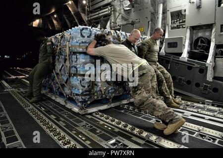 Die 3d-Luftbrücke der Squadron erreichen 7170 Crew und 123 Contingency Response Group Flieger entladen Essen und Wasser aus einem C-17 Globemaster III der Hurrikan Überlebenden von San Juan Luis Muñoz Marín Flughafen in San Juan, Puerto Rico verteilt werden, an Sept. 30, 2017. Reach 7170 gelieferten 118 tausend Pfund von Mahlzeiten bereit zu Essen und Mineralwasser in einem verwüsteten Puerto Rico mit Hilfe der Flieger aus der 123 Contingency Response Group verteilt werden. Stockfoto