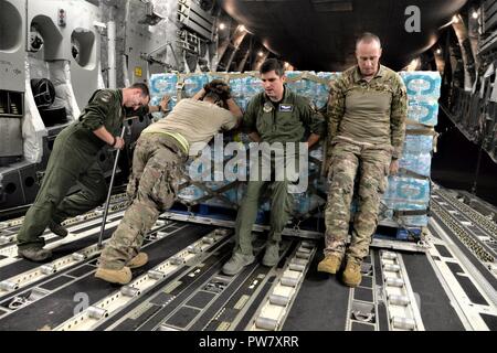 Die 3d-Luftbrücke der Squadron erreichen 7170 Crew und 123 Contingency Response Group Flieger entladen Essen und Wasser aus einem C-17 Globemaster III der Hurrikan Überlebenden von San Juan Luis Muñoz Marín Flughafen in San Juan, Puerto Rico verteilt werden, an Sept. 30, 2017. Reach 7170 gelieferten 118 tausend Pfund von Mahlzeiten bereit zu Essen und Mineralwasser in einem verwüsteten Puerto Rico mit Hilfe der Flieger aus der 123 Contingency Response Group verteilt werden. Stockfoto