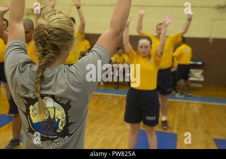 NORFOLK (Sept. 22, 2017) - der bootsmann Mate 3. Klasse Cassidy Belcher, ein Assistent, der Befehl fitness Leader an Bord der Nimitz-Class Flugzeugträger USS George Washington (CVN 73) führt die Aufwärmübungen für Segler, bevor Sie die physische Bereitschaft die Prüfung zu beginnen. George Washington befindet sich in einem Tank- und komplexen Überholung (RCOH) bei Newport News Werft. RCOH ist ein fast 4-jährigen Projekt nur einmal während einer Fluggesellschaft, die 50-jährige Nutzungsdauer, einschließlich Betankung von zwei nukleare Reaktoren des Schiffes sowie erhebliche Reparaturen, Upgrades und Modernisierung. Stockfoto